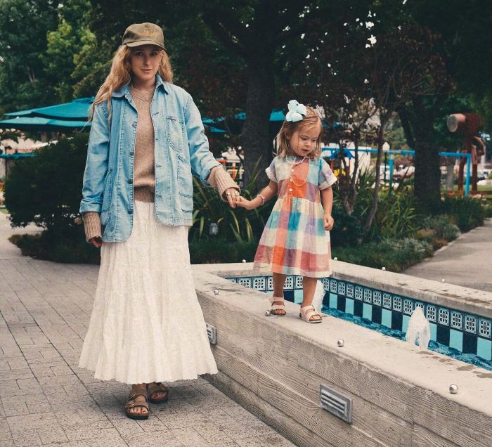 Bruce Willis' daughter and a young girl holding hands while walking near a fountain sharing dementia update.