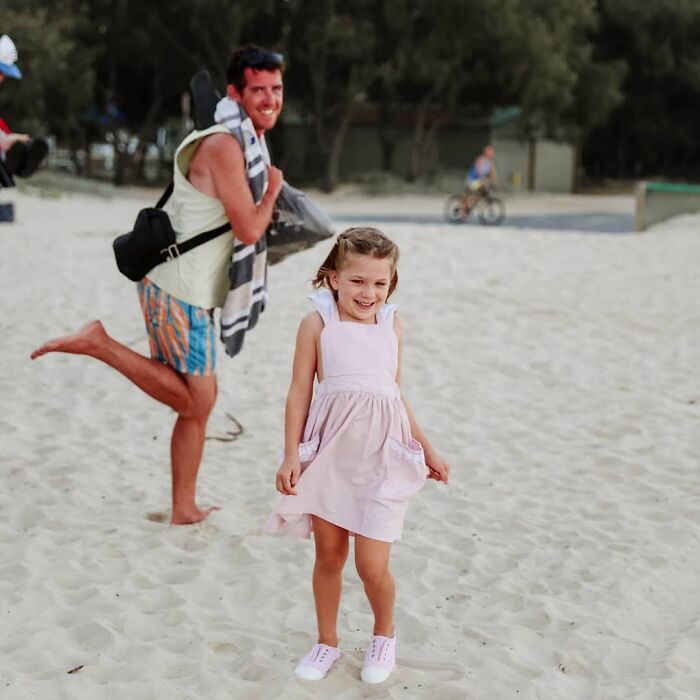 A man photobombing a smiling young girl on the beach, creating an epic photobomb that made everyone laugh.