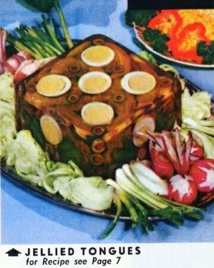 Vintage jellied tongue recipe garnished with hard-boiled eggs and fresh vegetables, showcasing disturbing vintage recipes.