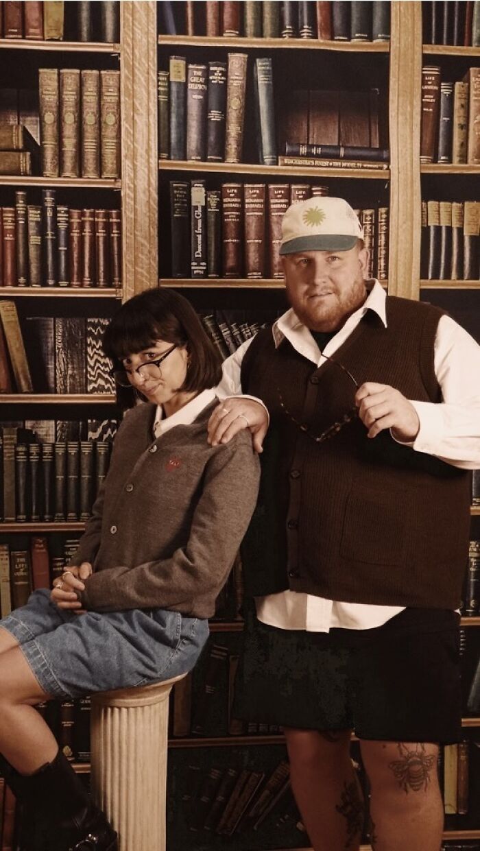 Two people posing awkwardly in front of a bookcase backdrop, capturing one of the awkward studio pics moments