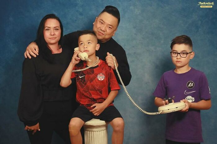 Family posing for an awkward studio photo with a vintage phone prop, creating a cringeworthy but memorable moment.