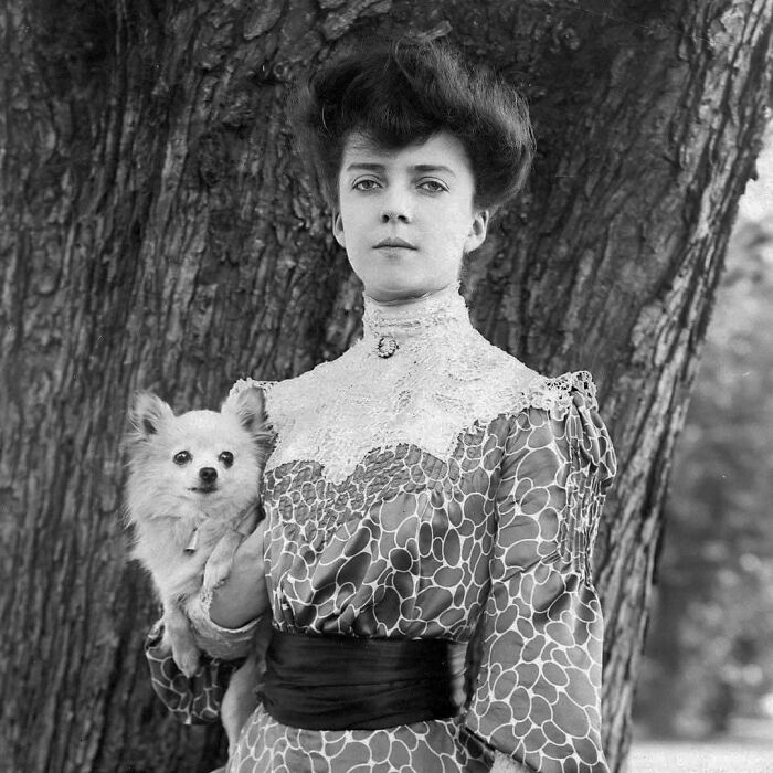 Victorian era woman in patterned dress holding a small dog, showcasing weird photos from the Victorian era.