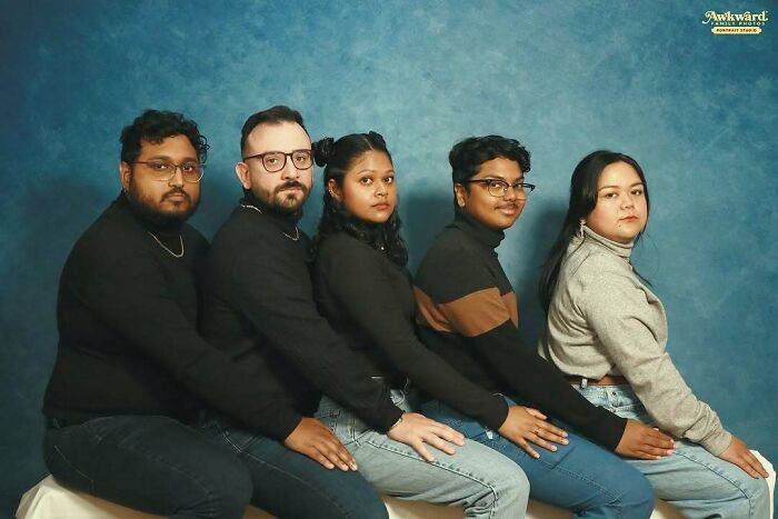 Five people dressed in casual clothes posing awkwardly in a studio setting for awkward studio pics.