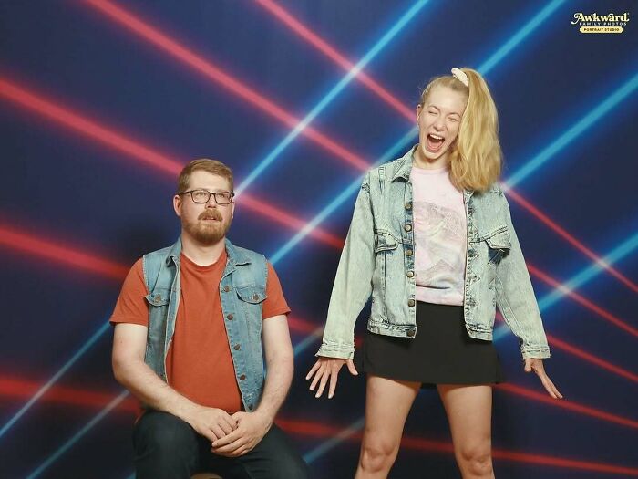 Man sitting with neutral expression and woman laughing in awkward studio pics with colorful neon light background.