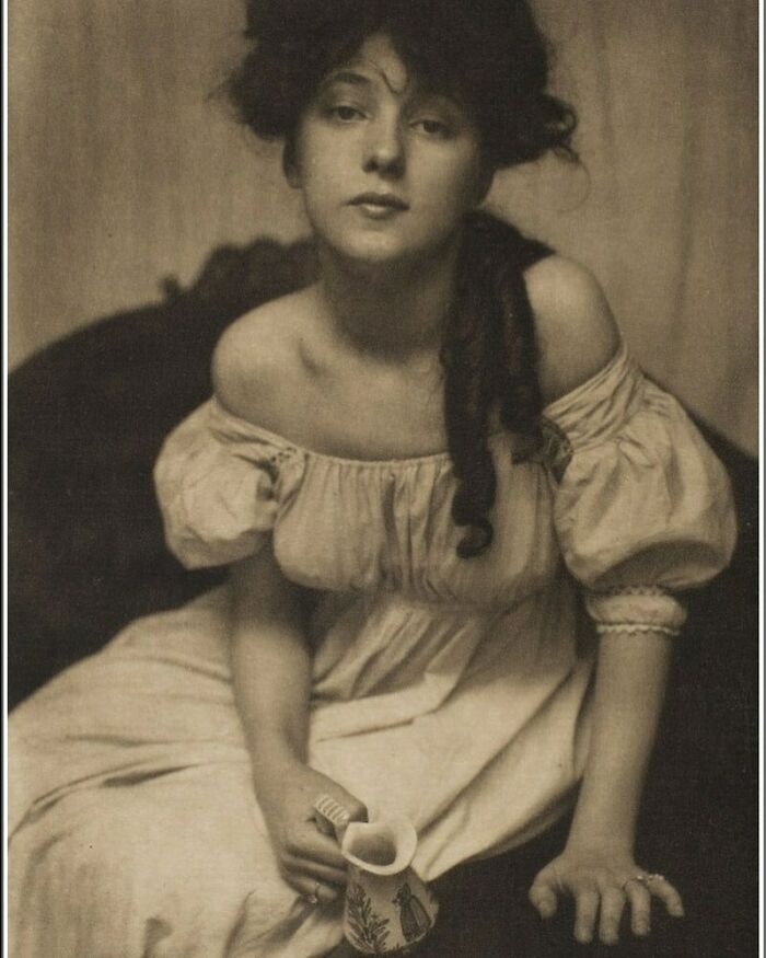 Young woman in a Victorian era dress holding a cup, captured in a weird photo reflecting the Victorian era style.