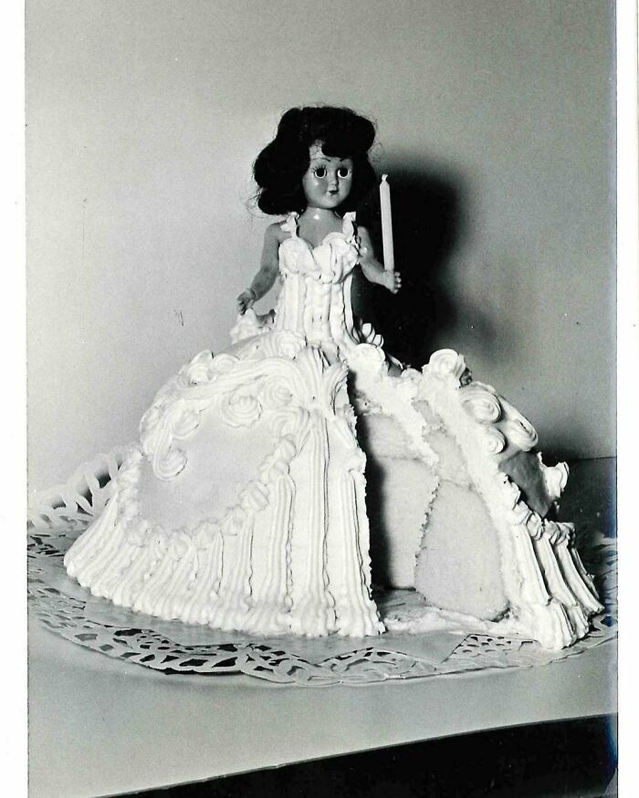 Vintage doll cake with detailed frosting and a candle, showcasing disturbingly creative vintage recipes from Gen X era.