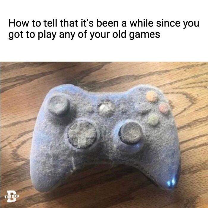 Dust-covered old gaming controller on wooden surface showing signs of not playing games for a long time in funny dad meme.