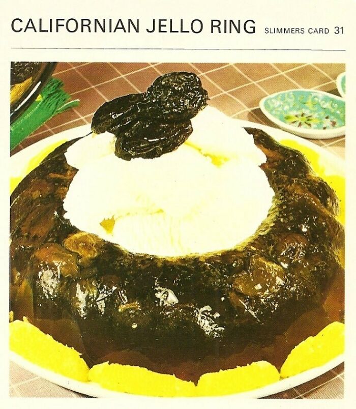 Disturbingly creative vintage recipe of a dark Californiam Jello ring topped with whipped cream and prunes on a plate.