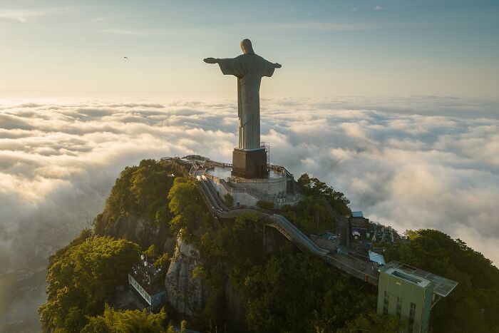 Christ the Redeemer statue atop Corcovado Mountain surrounded by clouds, a spectacular sculpture popular for travel bucket lists.