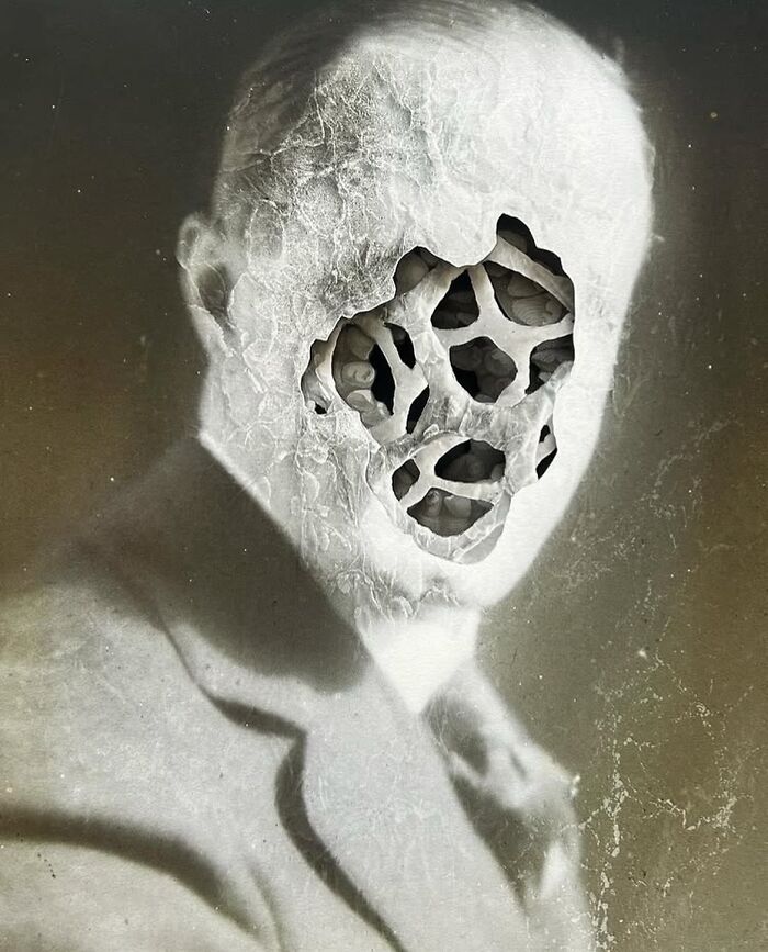 Black and white intricate collage of a man with a hollow, web-like structure where his face should be, creating a surreal effect.