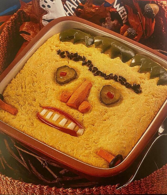 Vintage creepy casserole dish decorated with pickles, carrots, and olives, showcasing disturbingly creative vintage recipes.