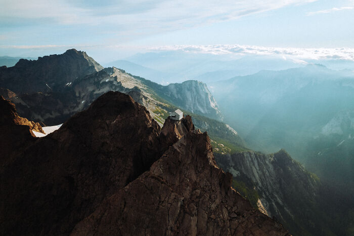 Mountain peak with a small cabin surrounded by vast landscape, reflecting a journey to find direction and purpose.