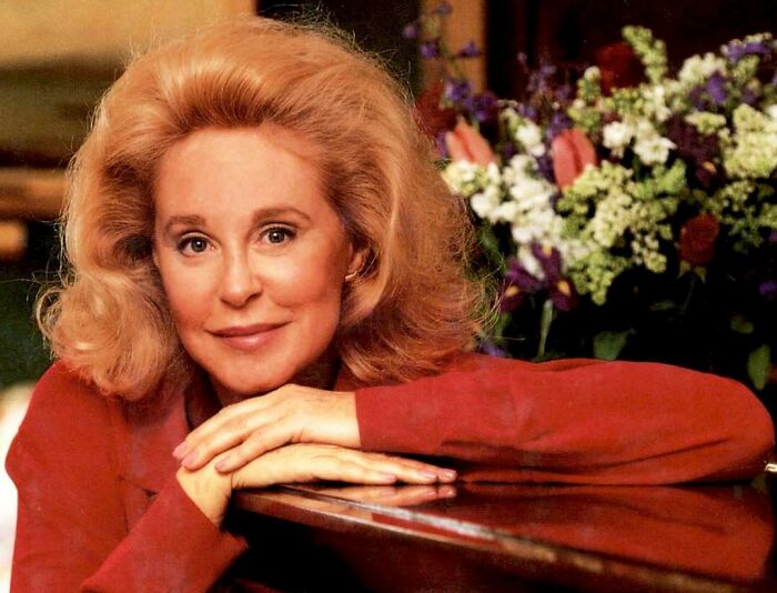 Portrait of a woman with blonde hair leaning on a table, representing women overlooked in history and their achievements.