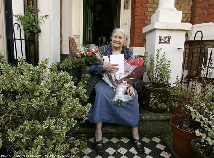 Elderly woman sitting on porch steps holding flowers, representing overlooked women and their important achievements in history.
