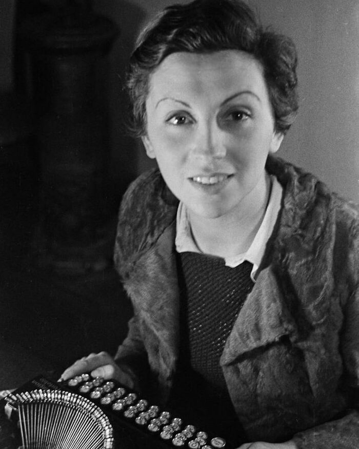 Black and white photo of a woman with short hair playing an accordion, representing overlooked women in history achievements.
