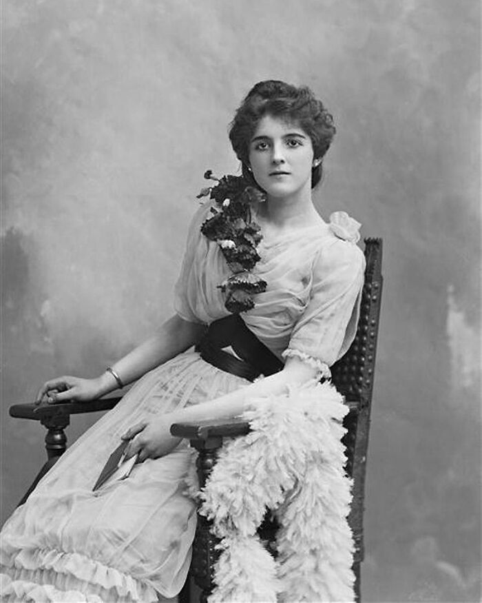 Black and white portrait of a woman in vintage dress seated on a chair representing overlooked women in history and achievements.