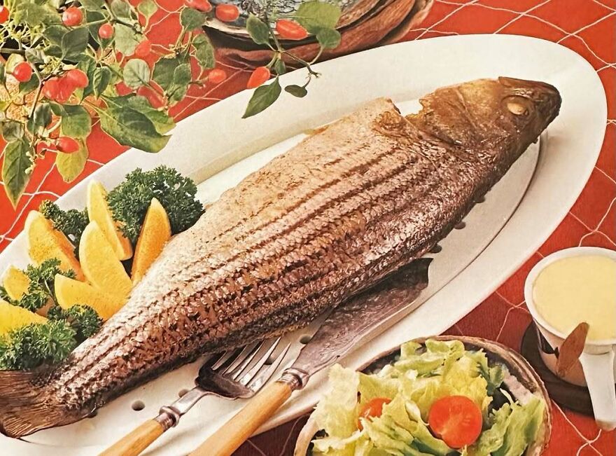 Vintage recipes featuring a whole cooked fish served with lemon wedges, greens, and a side salad on a retro tablecloth.