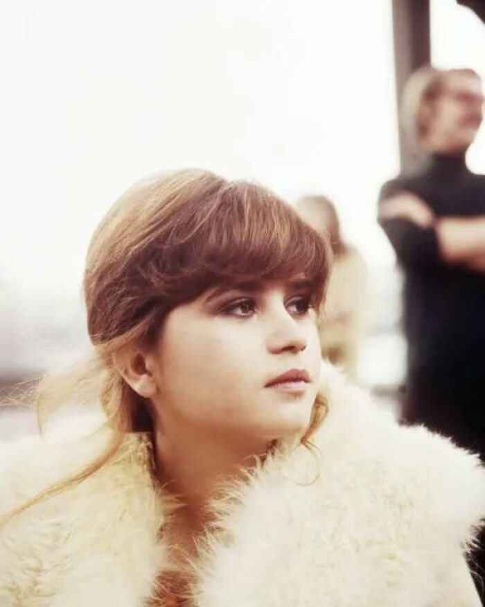 Young woman with brown hair wearing a fur coat, representing overlooked women in history with important achievements.