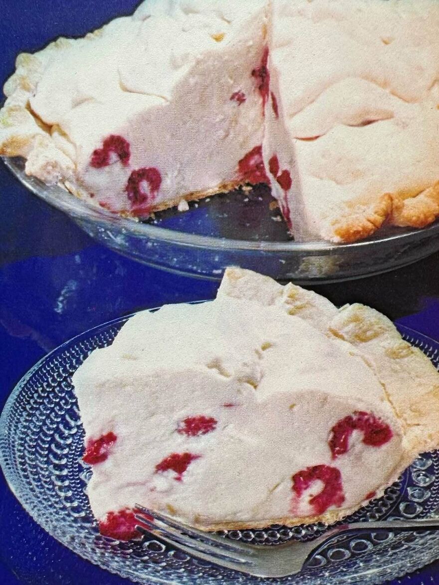Slice of vintage pie with a fluffy white filling and red berries, showcasing interesting vintage recipes from the past.