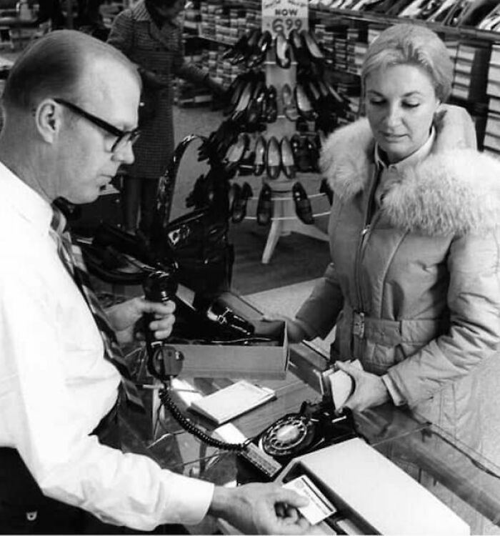 Man assisting woman with shoe purchase in a vintage store, representing women overlooked in history and their achievements.