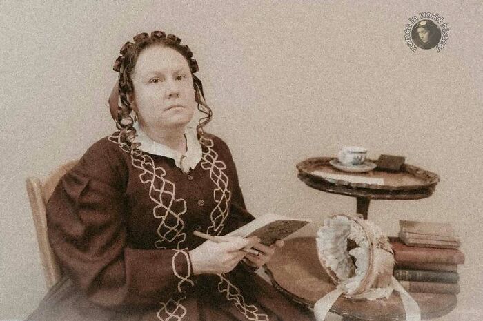 Sepia photo of a woman in vintage dress holding a book, representing overlooked women in history and their achievements.