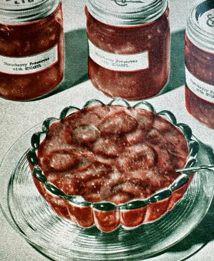 Vintage recipe dish with a gelatin dessert in a scalloped glass bowl, surrounded by jars of homemade preserves and jams.