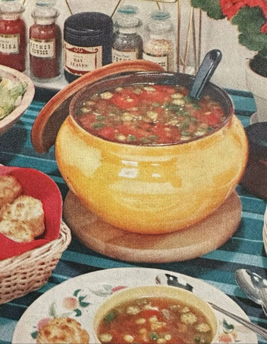 Vintage recipes featuring a yellow pottery soup tureen filled with a tomato-based soup on a retro dining table setting.