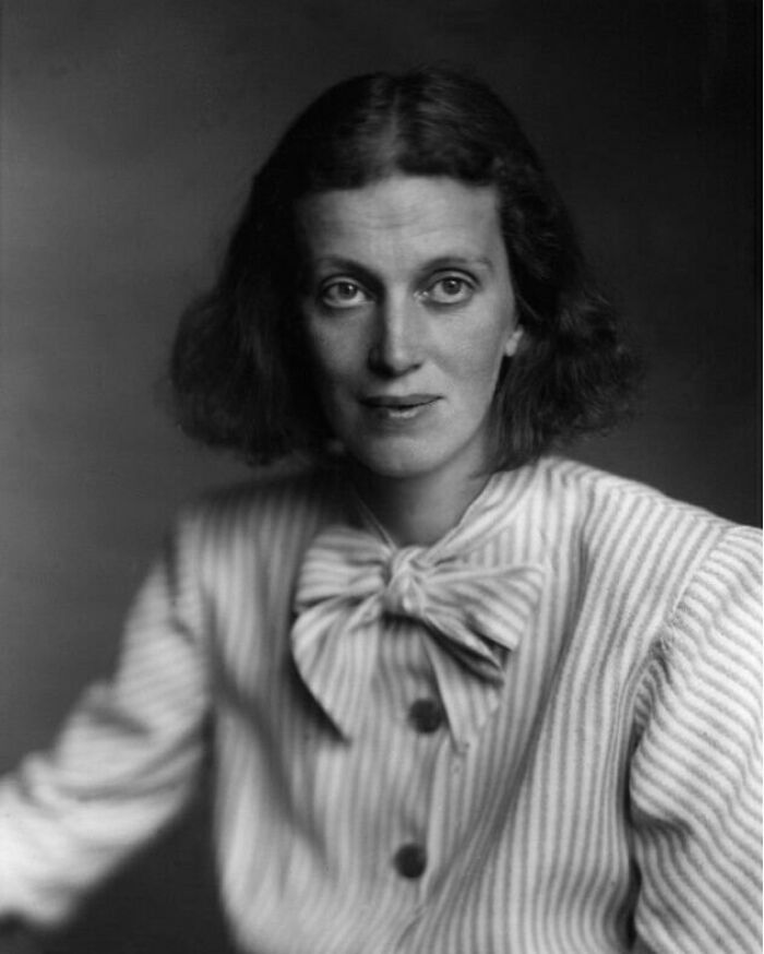 Black and white portrait of a woman with short hair wearing a striped blouse with a large bow, representing overlooked women in history.