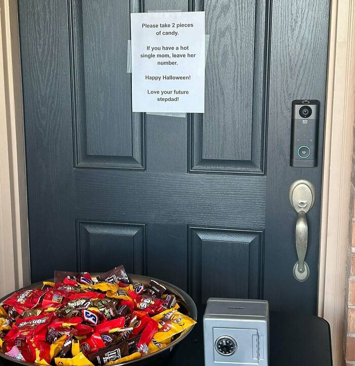Bowl of candy on a table in front of a door with a humorous sign, perfect for entertaining posts and memes.