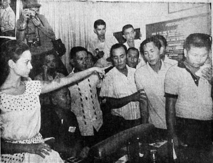 Woman in polka dot dress pointing amid a group of men in a historic moment highlighting overlooked women in history.