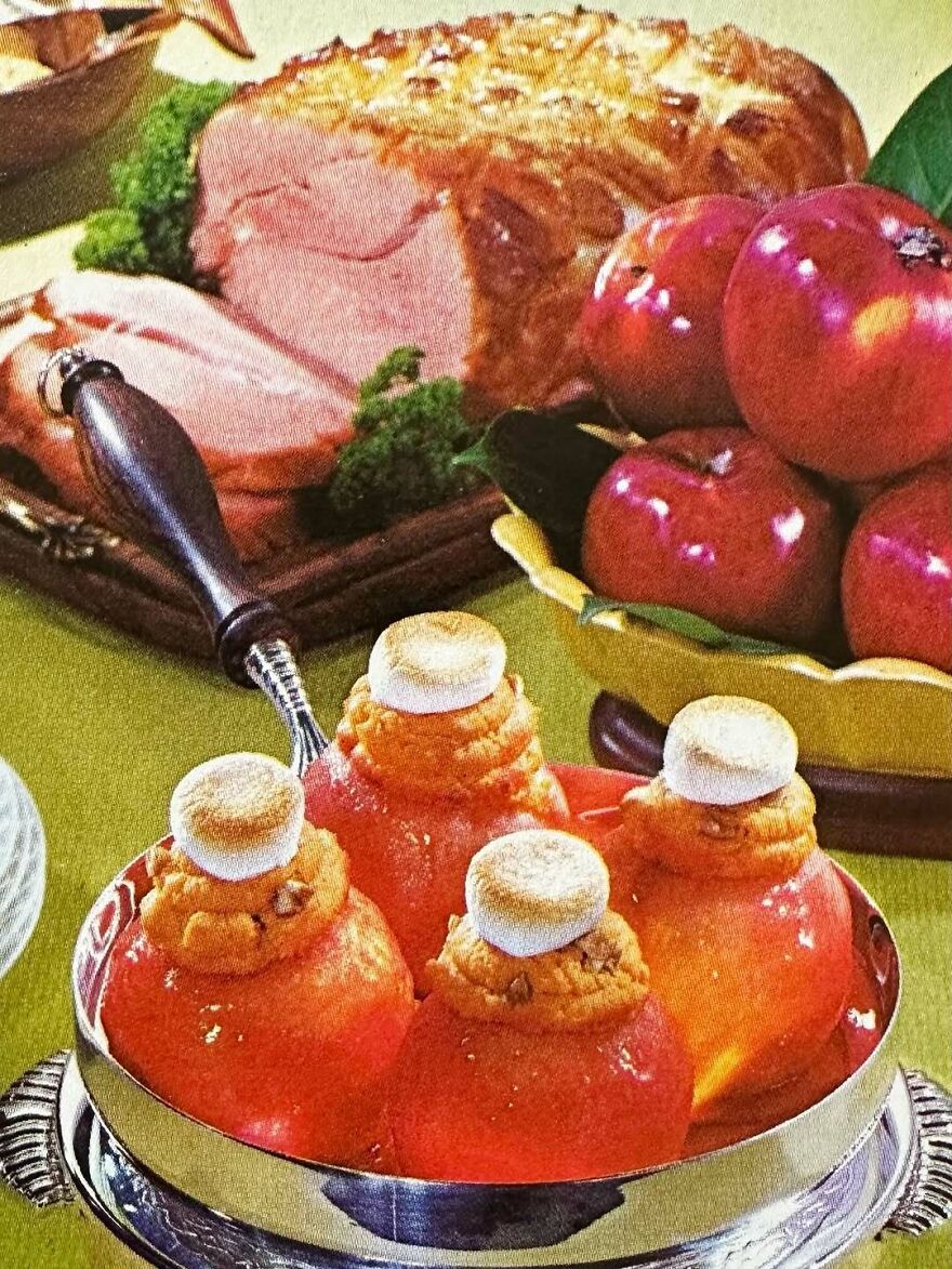 Vintage recipes featuring stuffed gelatin molds topped with toasted marshmallows alongside ham and fresh apples on a dining table.