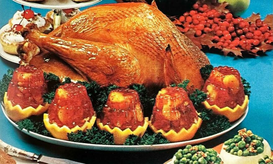 Vintage roasted turkey platter surrounded by gelatin mold side dishes showcasing interesting vintage recipes.