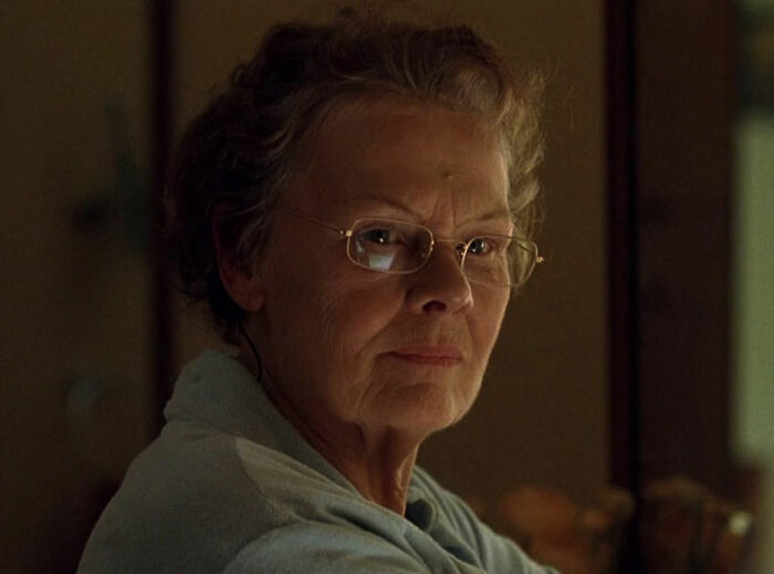 Dame Judi Dench wearing glasses, looking thoughtful indoors, sharing a heartbreaking health confession on camera.