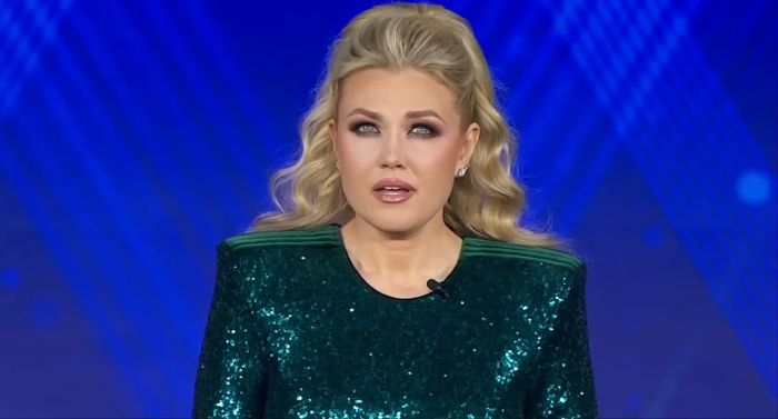 Erika Kirk speaking on stage in a green sequined dress, linked to touchy-feely hug controversy with country singer.