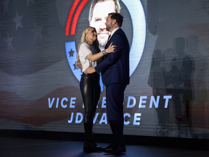 Erika Kirk and JD Vance share an emotional moment on stage at TPUSA event with Vice President JD Vance backdrop.