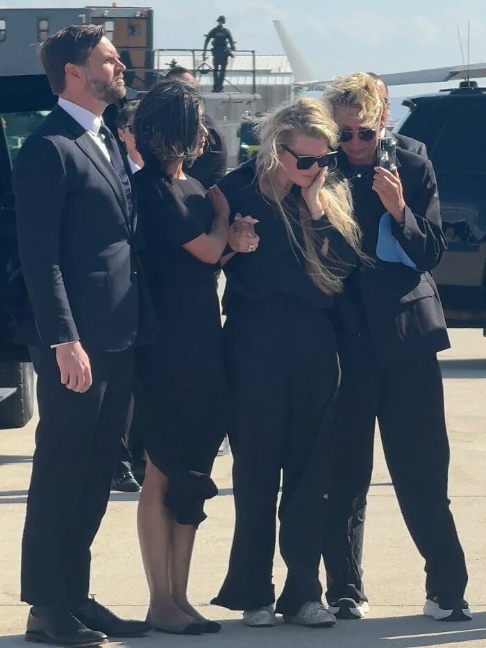 Erika Kirk and others in black outfits sharing an emotional moment, highlighting lip reader exchange at TPUSA event.