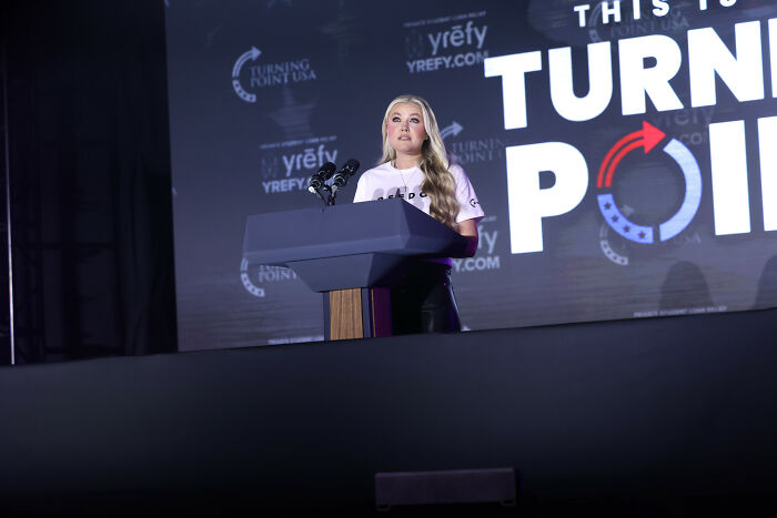 Erika Kirk speaking at Turning Point USA event, sharing emotional exchange with JD Vance as lip reader reveals details.