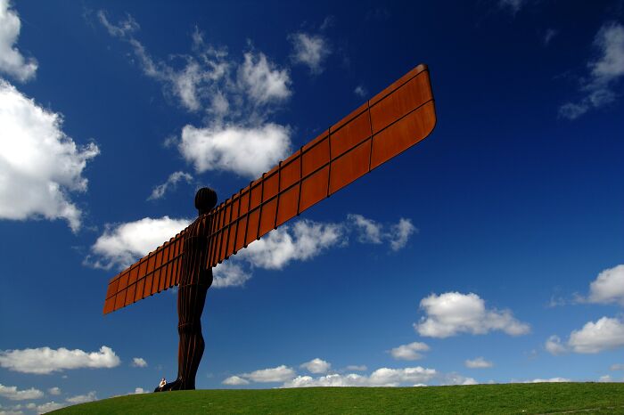 Angel of the North sculpture standing on a hill under a blue sky, a spectacular sculpture popular with global travelers