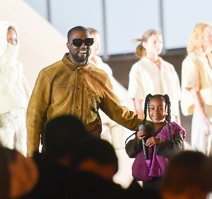 Kanye West with daughter Blue Ivy on stage, spotlighting celebrity parenting and the challenges of kids born into fame.