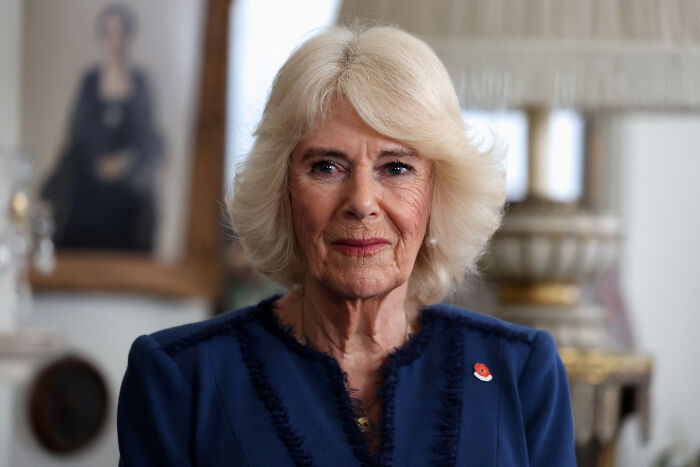 Queen Camilla wearing a blue outfit indoors, reflecting the female touch influencing Andrew&rsquo;s title removal decision.