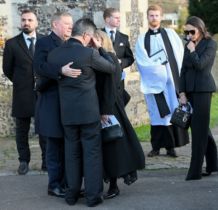 Mourners dressed in black at a solemn outdoor gathering, related to Simon Cowell and Liam Payne mental health discussion.