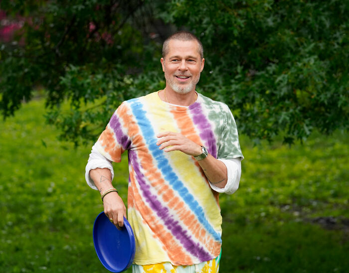 Brad Pitt wearing a colorful tie-dye shirt outdoors, sparking speculation about his appearance at Hollywood premiere.