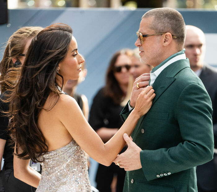 Brad Pitt at Hollywood premiere wearing green suit and sunglasses, sparking speculation about his changed appearance.
