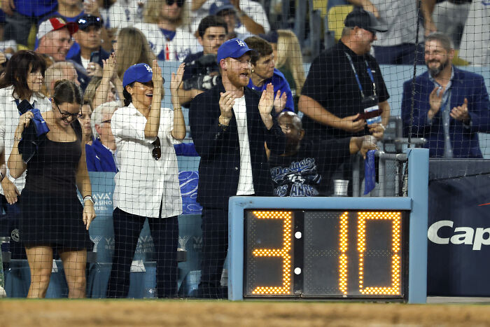 Prince Harry and Meghan Markle celebrating at a baseball game, sparking many to think the event was staged.