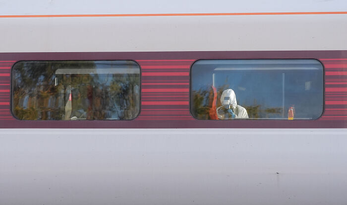 Person in protective suit inside UK train during rampage as hero old man blocks knife attack on girl.