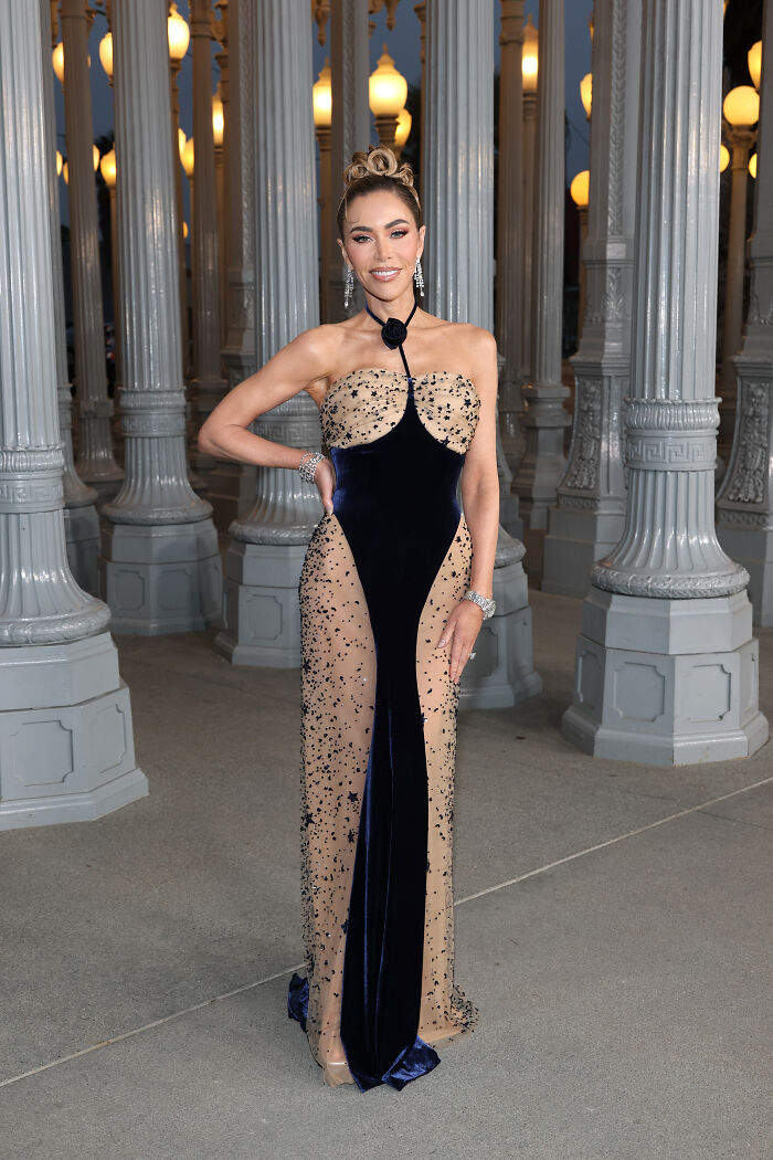 Woman in a sparkling navy and n**e gown posing among tall columns at the 2025 LACMA Art and Film Gala outfits.