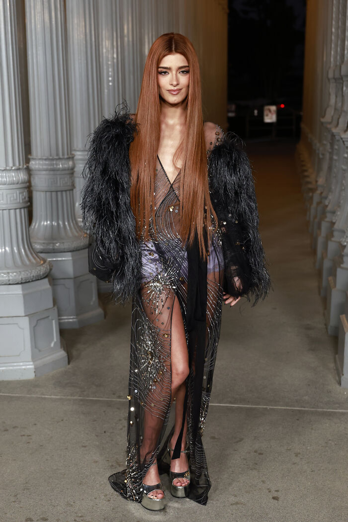 Model wearing a sheer embellished dress with a black feathered jacket at 2025 LACMA Art and Film Gala outfits.