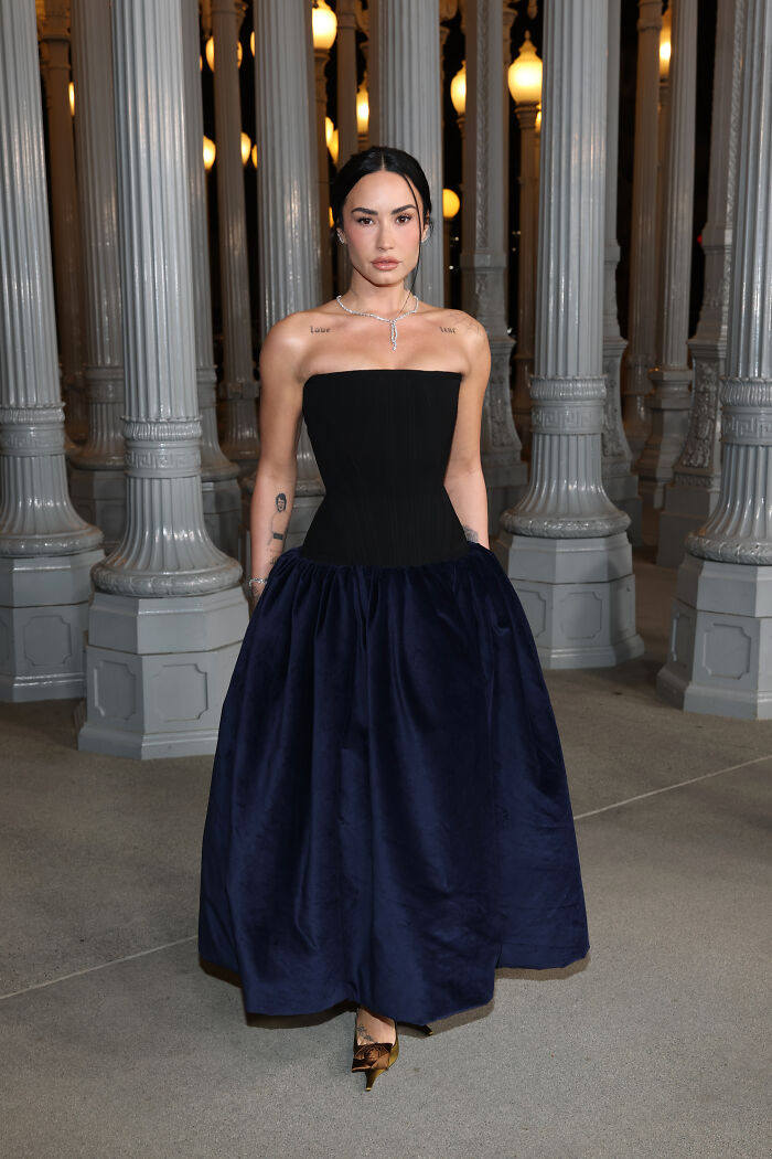 Woman in a strapless black and navy gown posing among tall art gallery lamps at 2025 LACMA Art and Film Gala outfits.