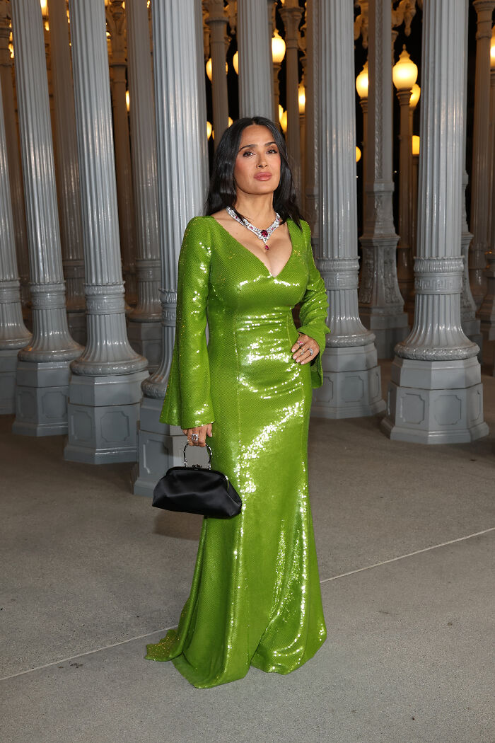 Woman in a shimmering green gown and statement necklace posing at the 2025 LACMA Art and Film Gala outfits event.