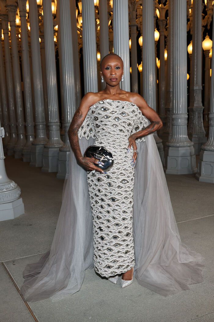 Elegant woman wearing a beaded gown with a sheer cape and silver clutch at 2025 LACMA Art and Film Gala outfits.